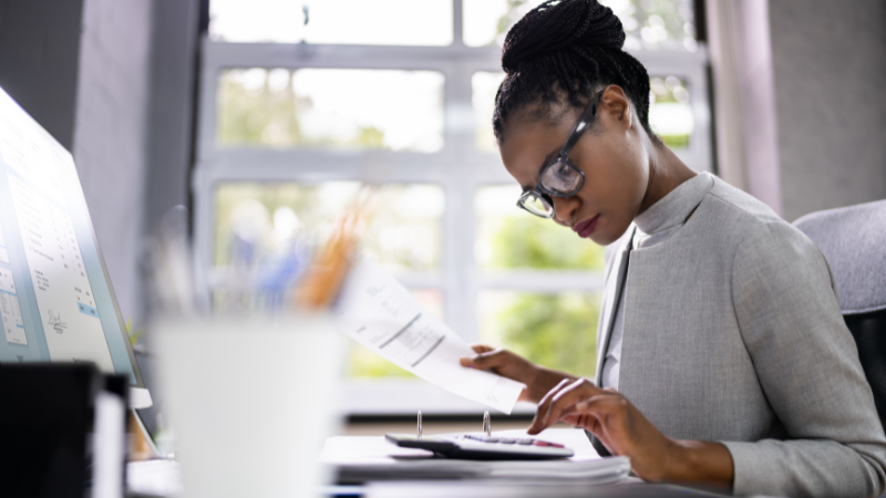 African American woman working with a calculator and an invoice