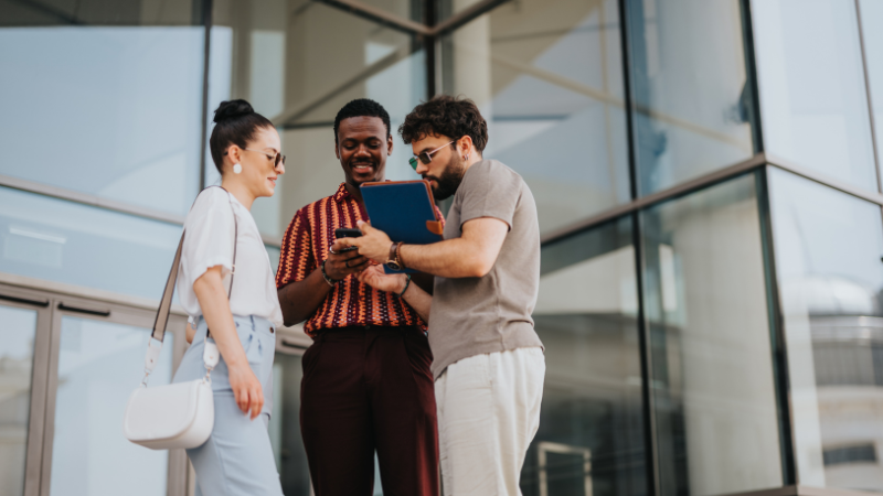 three Millennials standing in front of a high-rise building