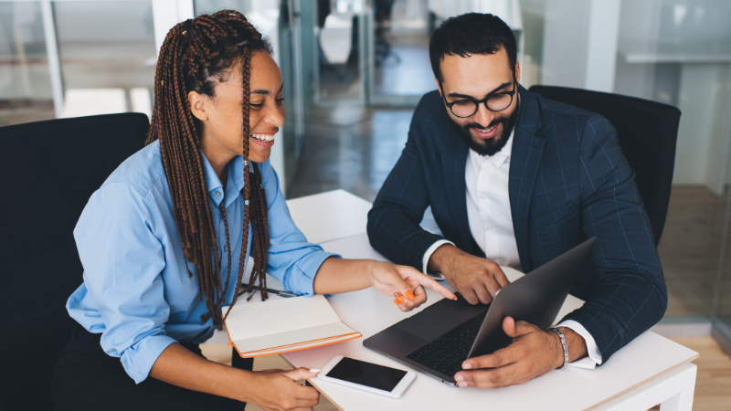 two people of color looking at a laptop talking business