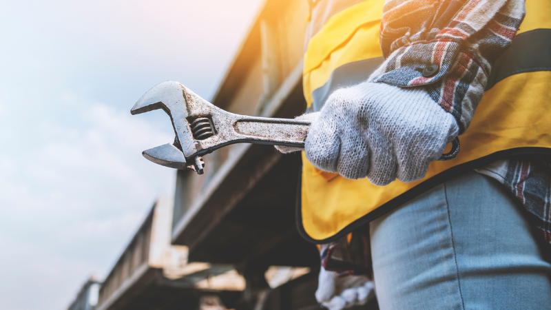 maintenance worker in yellow vest holding wrench
