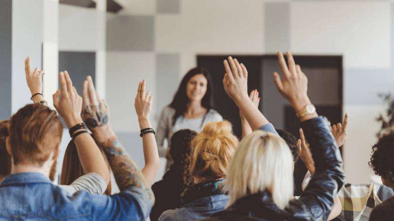 group of mixed people voting by raising their hand