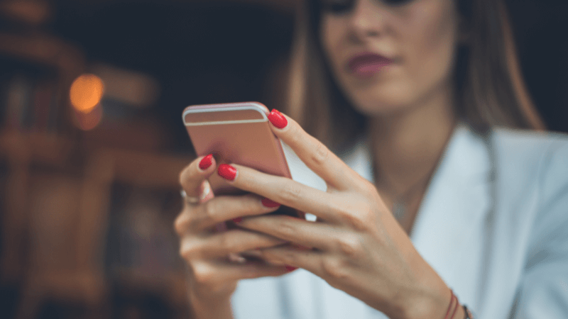 white lady with red nails on her cell phone
