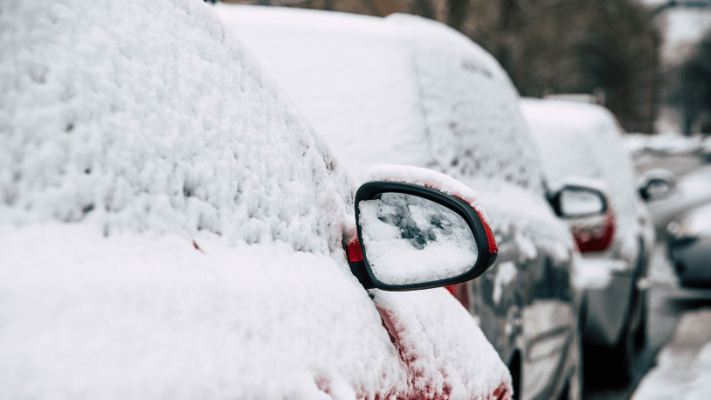 row of cars in a neighborhood covered in snow