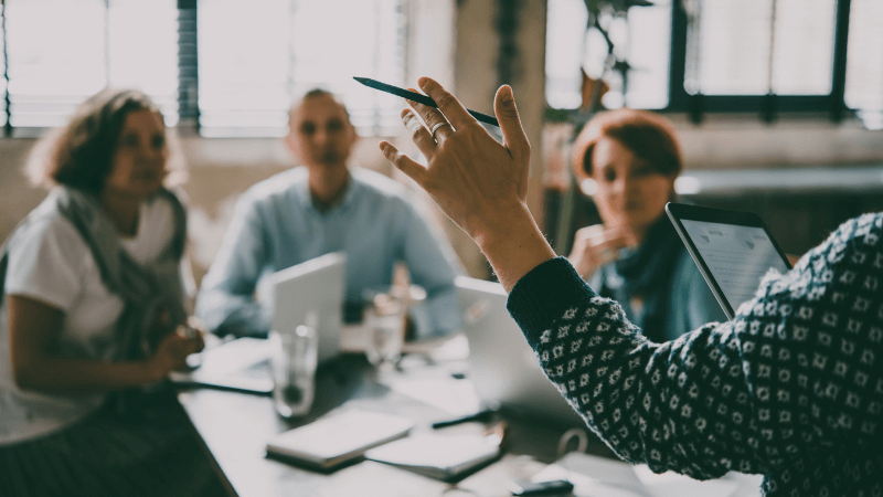 4 people in a business room with an ipad, holding a meeing 