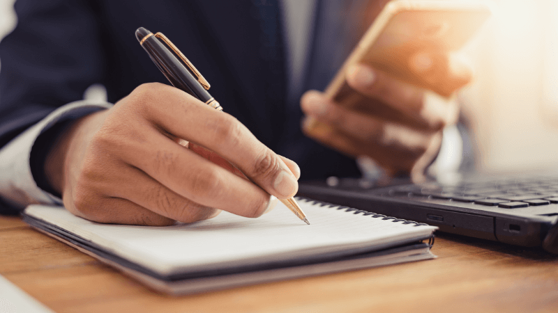 mixed race man's hand making a list with cellphone in hand 