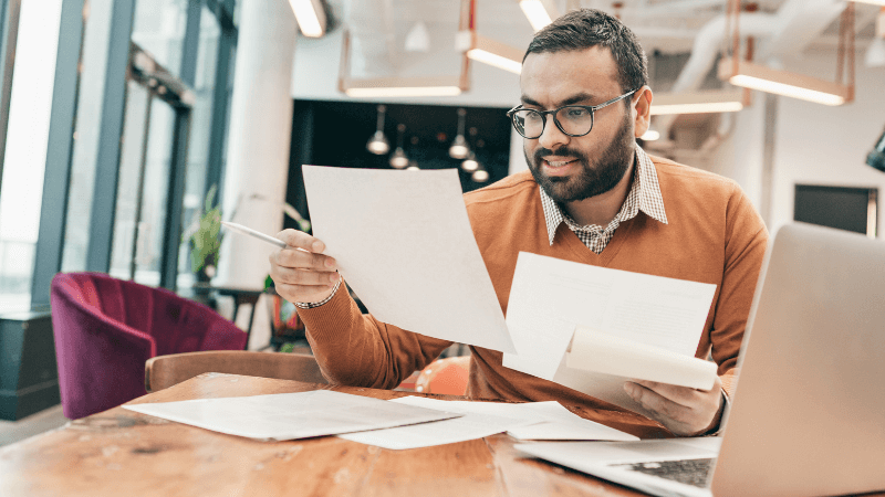 Indian man in yellow sweater looking at documents