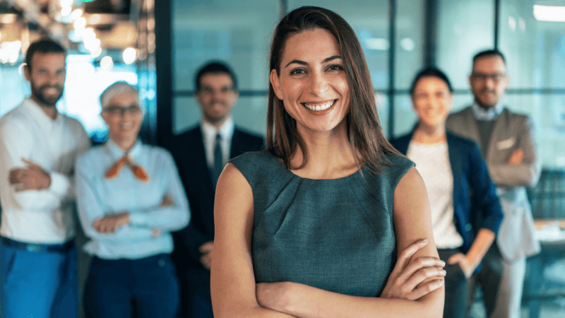 latina business woman standing in front of coworkers, being happy