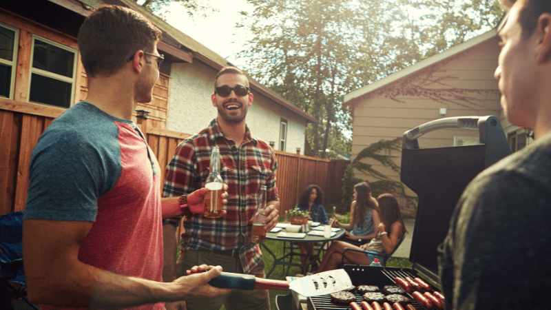three men in a backyard grilling