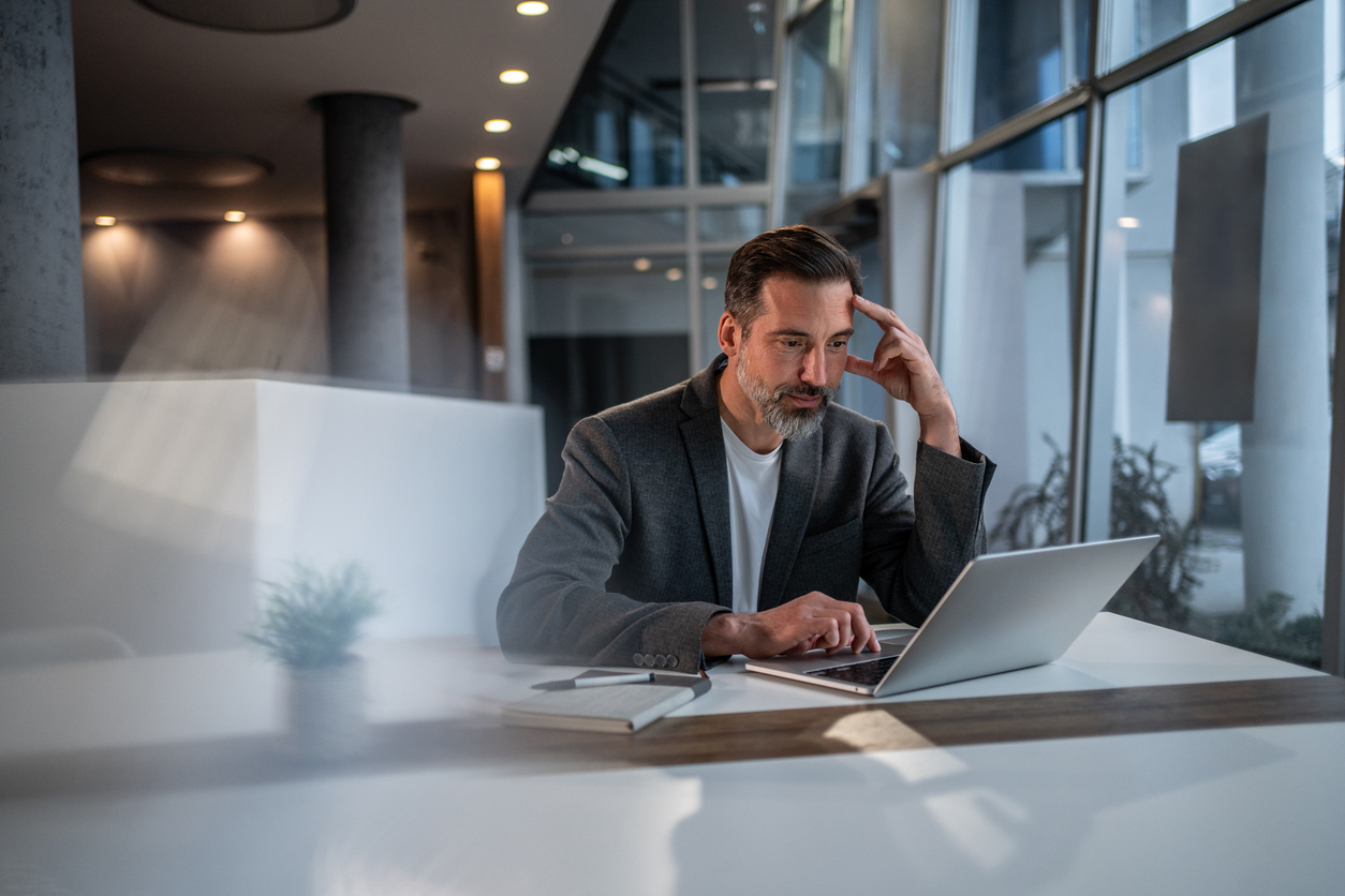 Man in his forties slumped over staring at his computer screen