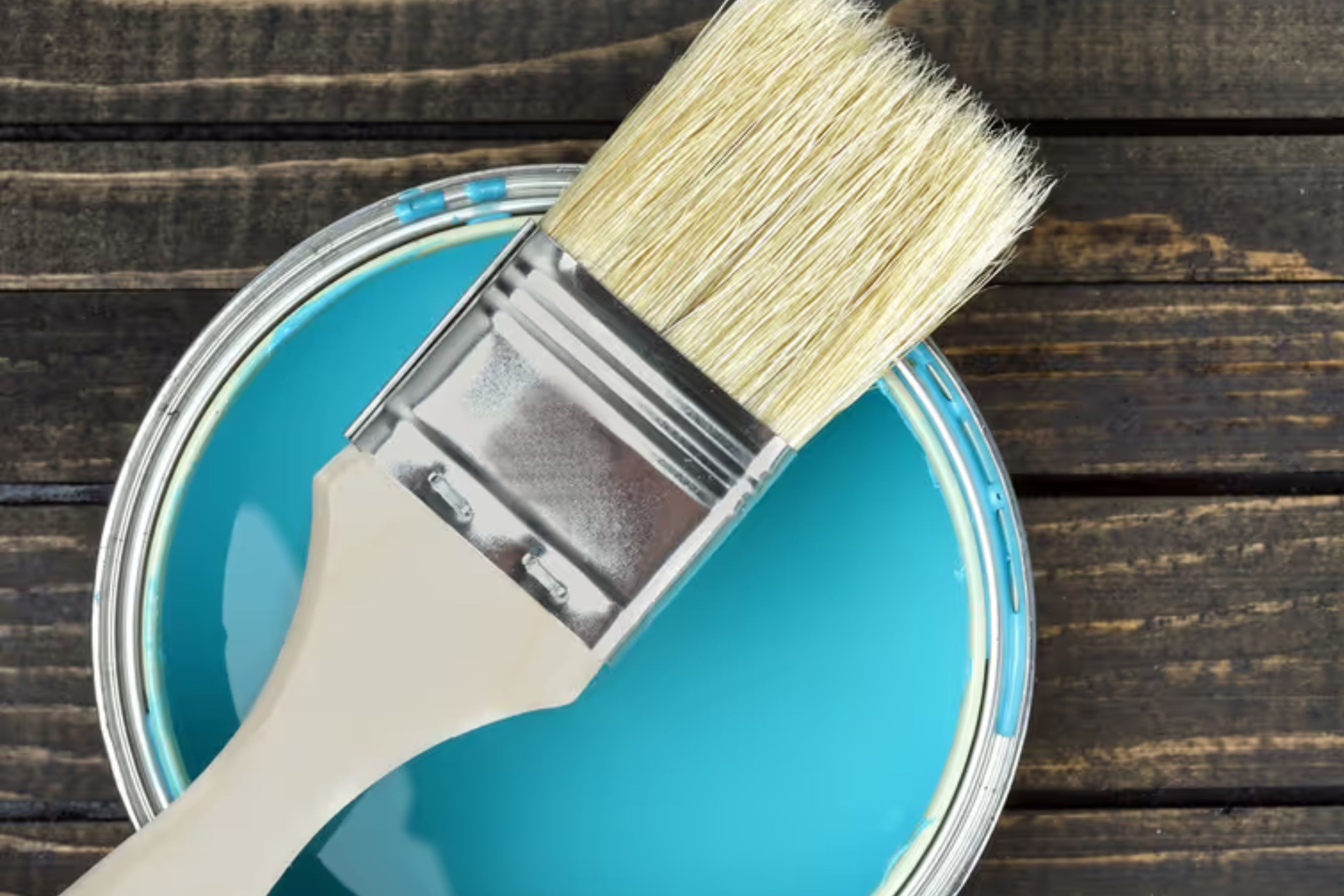 A paintbrush sits on a bucket - Whether you're a homeowner or a property manager, it's important to know your paints and primers.