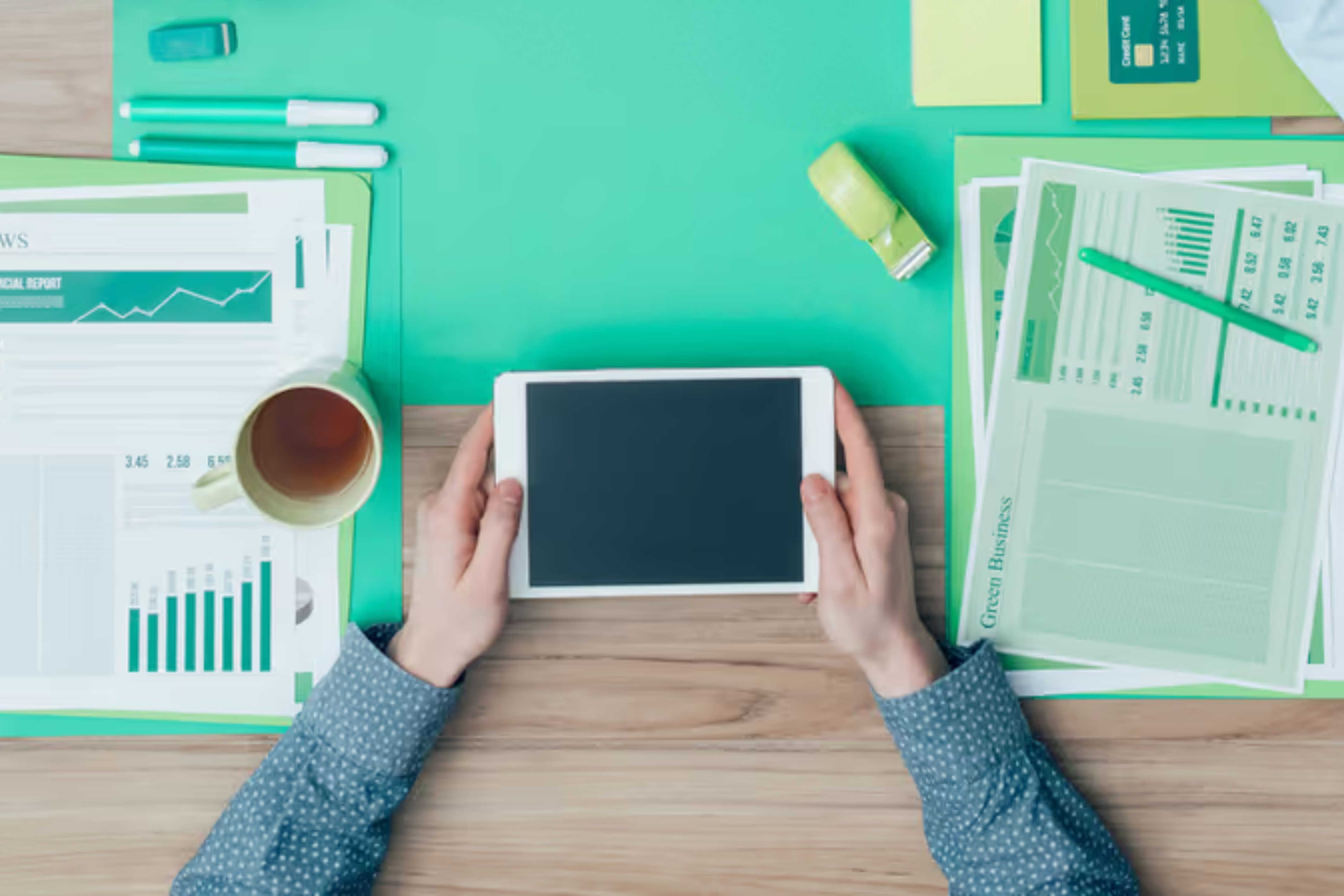 Hands hold a tablet with financial papers scattered around - Whether you're an HOA manager or a homeowner, organizational hacks can change your life.