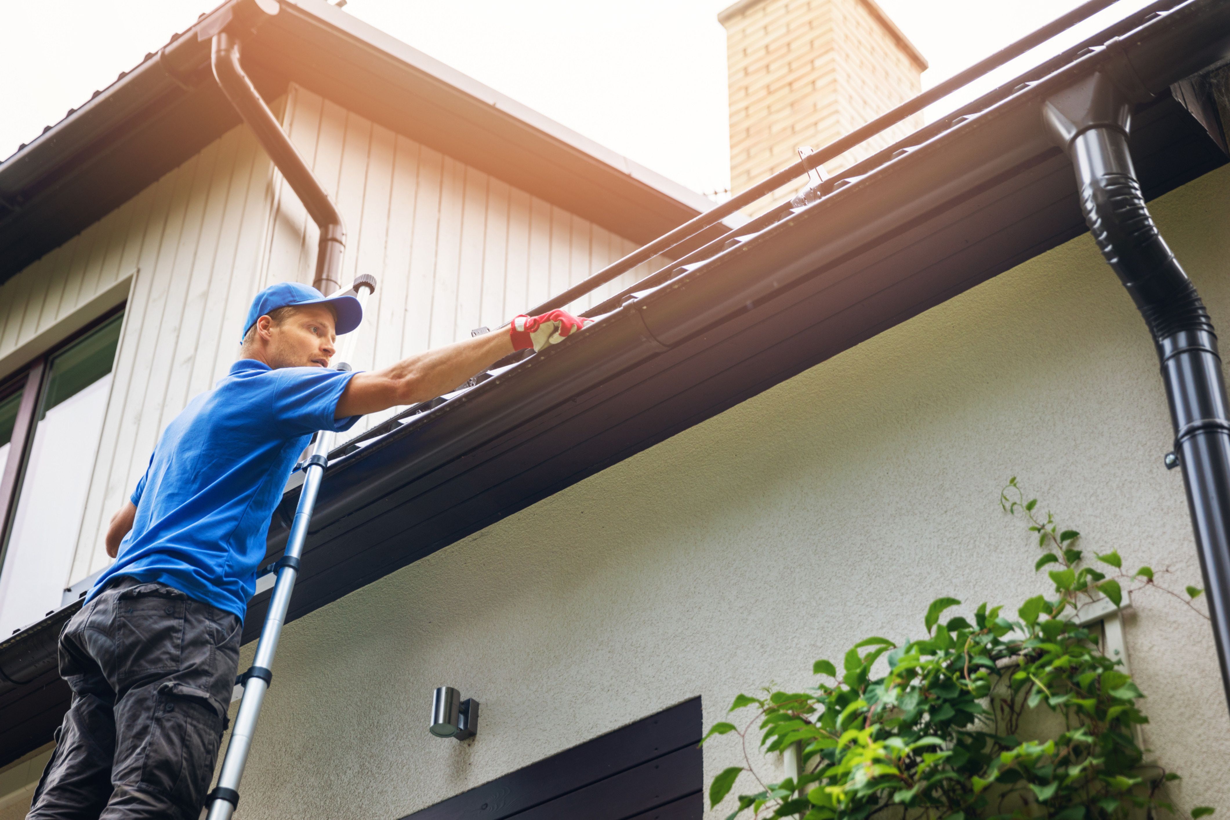 Man on a ladder conducts spring maintenance in his HOA community.