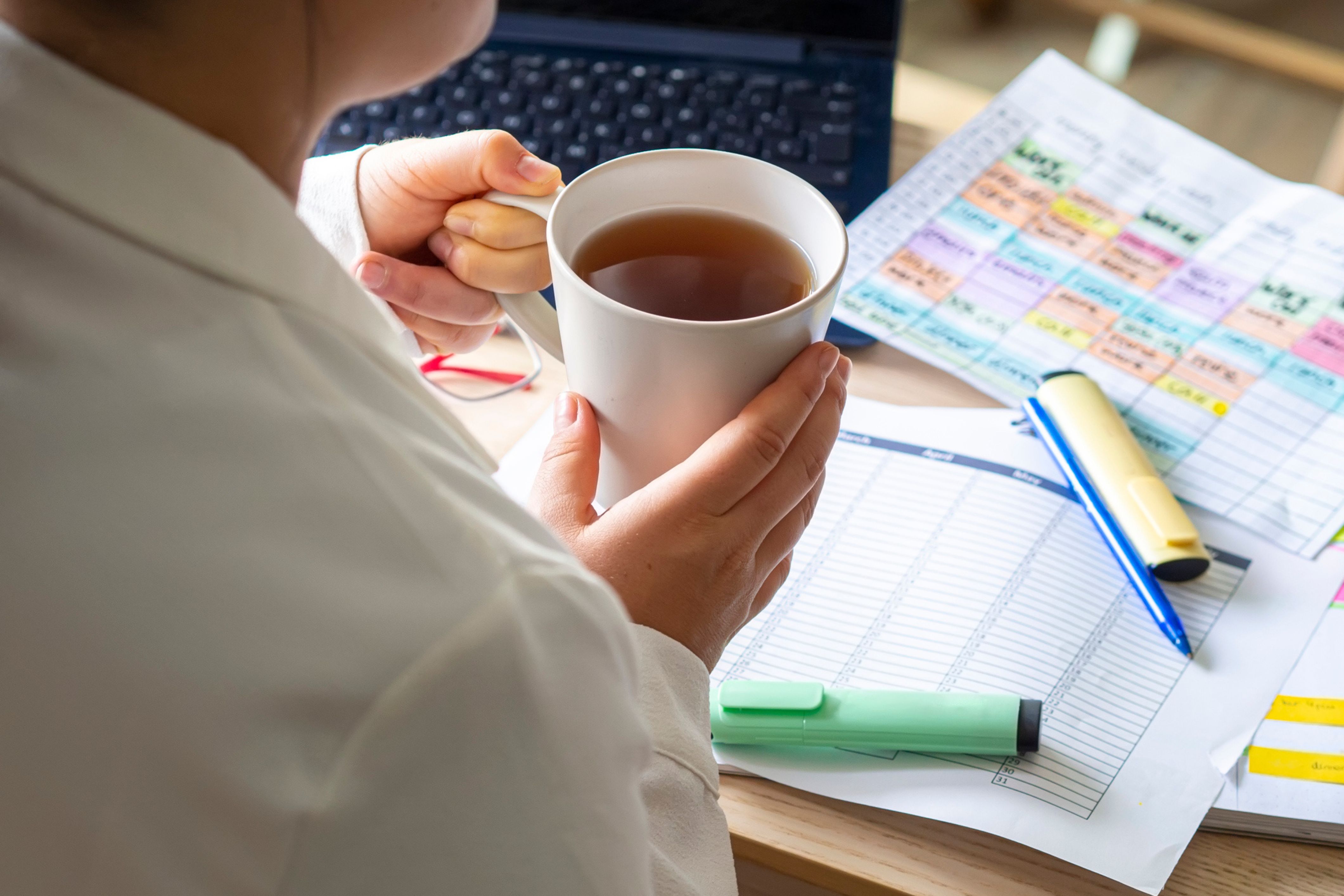 An extern holds coffee and checks out a highlighted schedule.