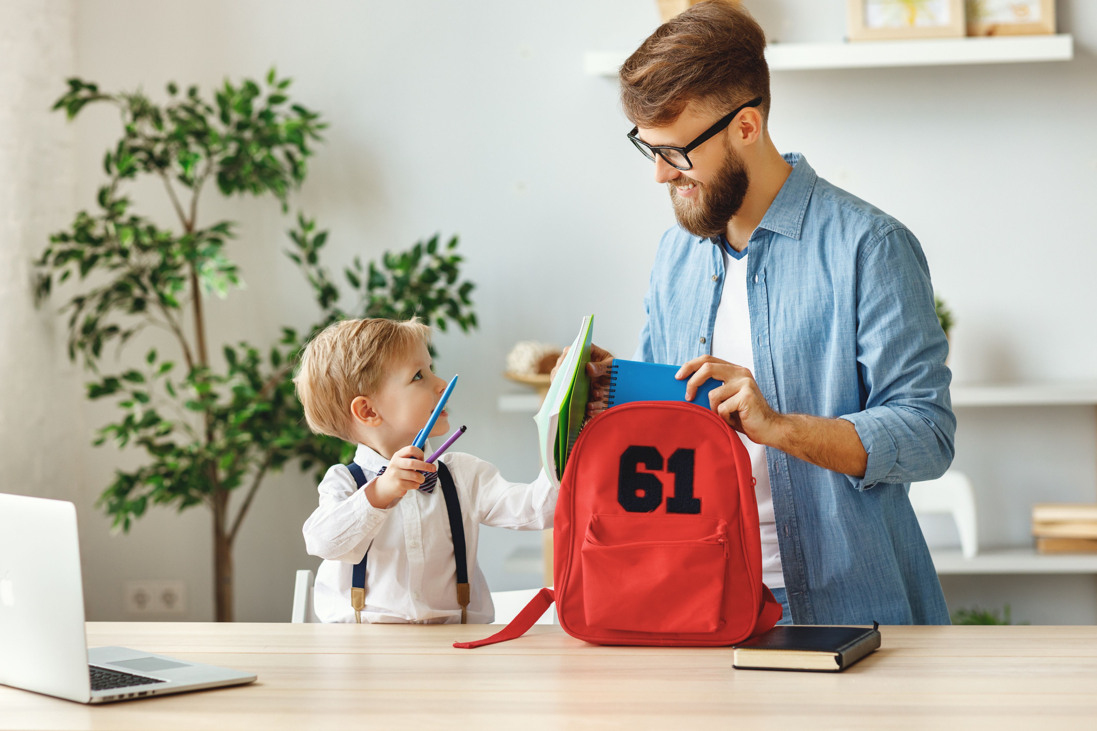 A father and his son pack a backpack together with our back-to-school tips.