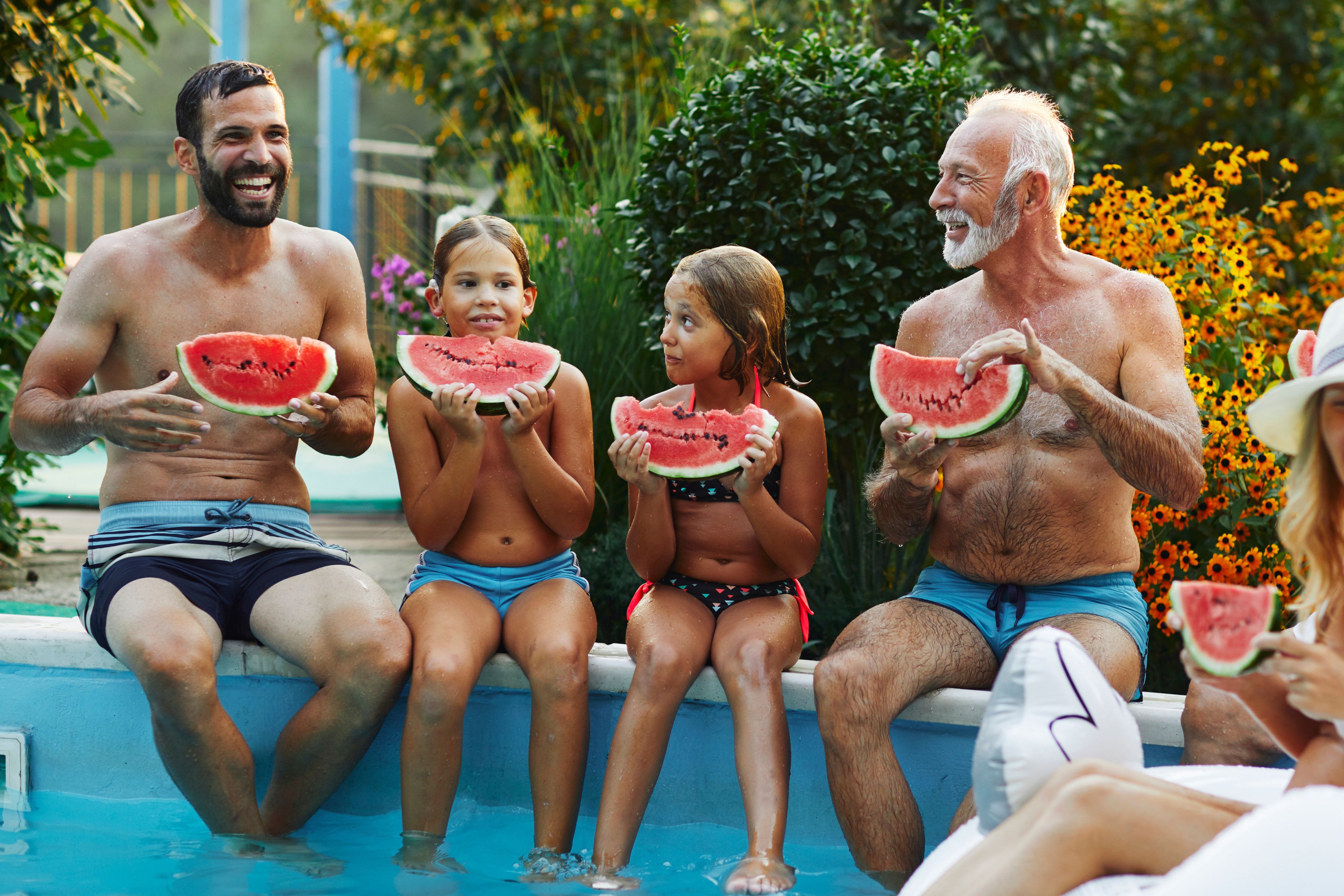 A family enjoys watermelon by the pool at their Labor Day cookout.