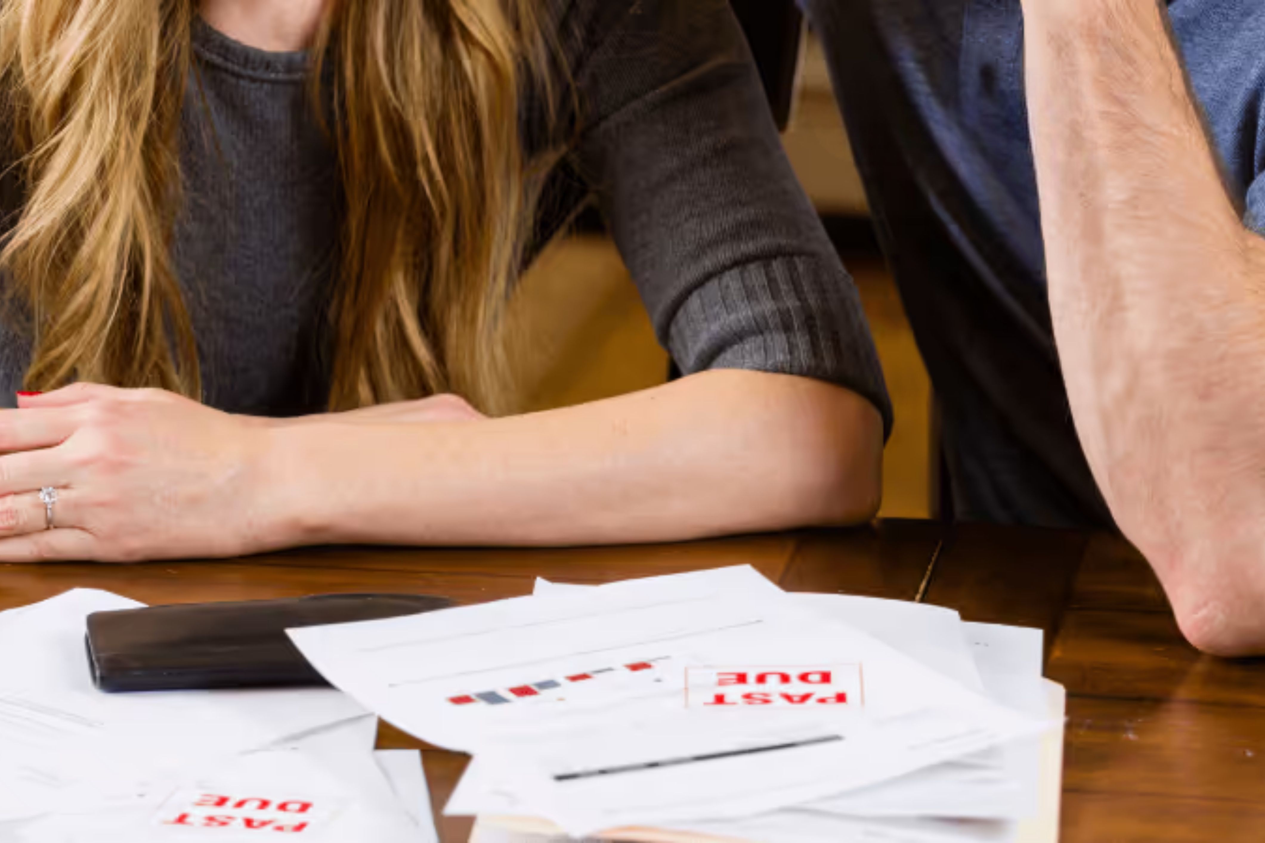 A couple sits next to bills that are past due - they could be facing their HOA's collection policy.