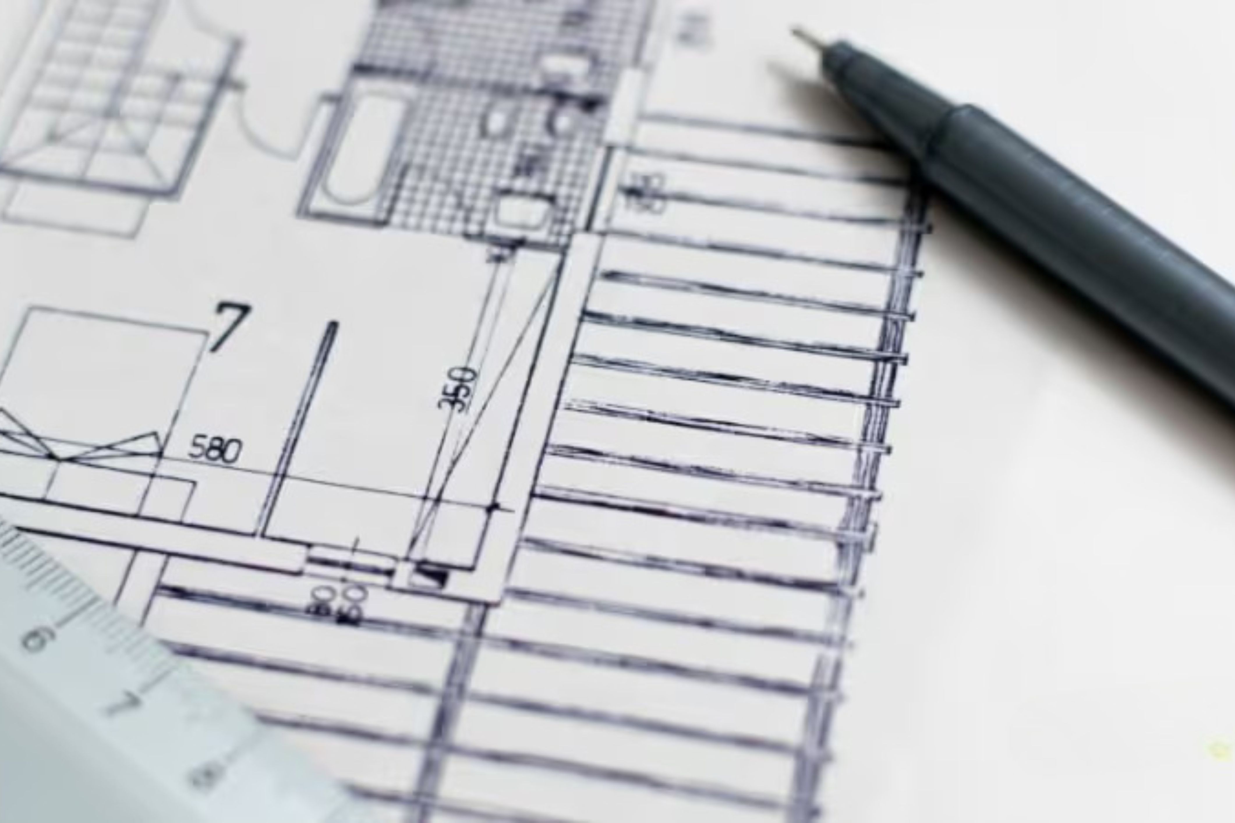 Architectural plans for a community sit on a desk with a pen.