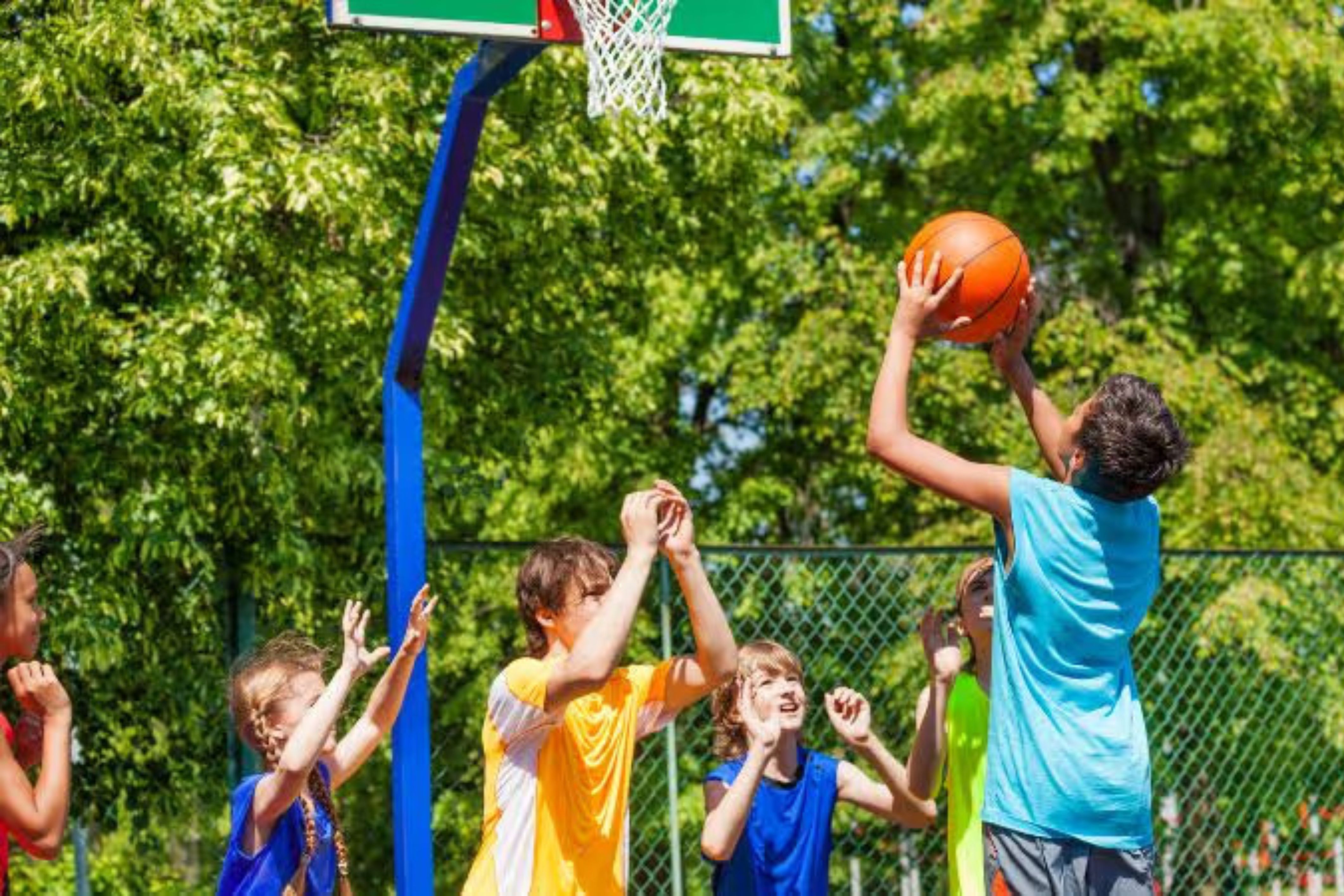 A group of children plays together on a basketball court in an HOA community.
