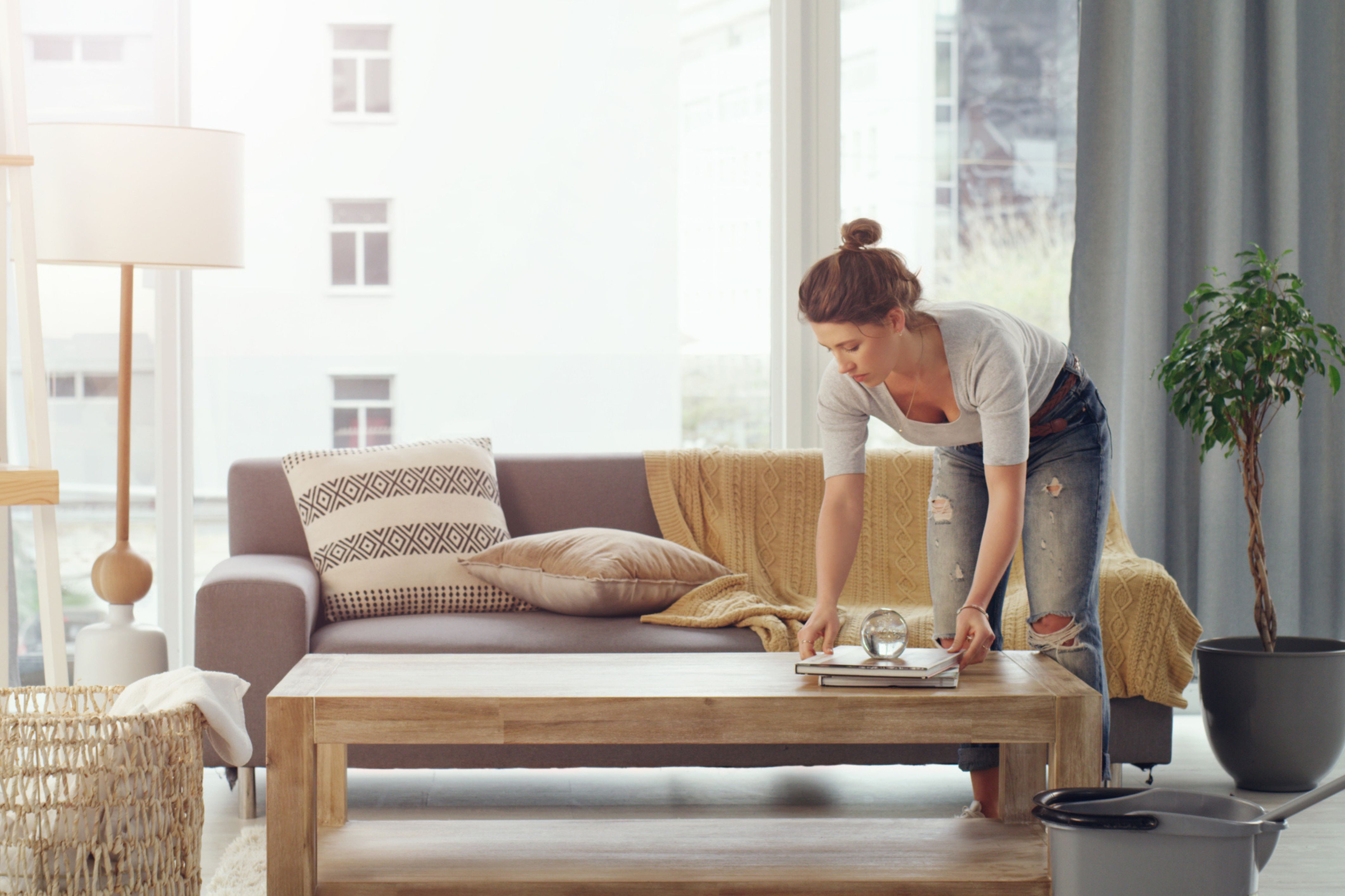 A woman organizes her living room, potentially prepping to get rid of old funiture.