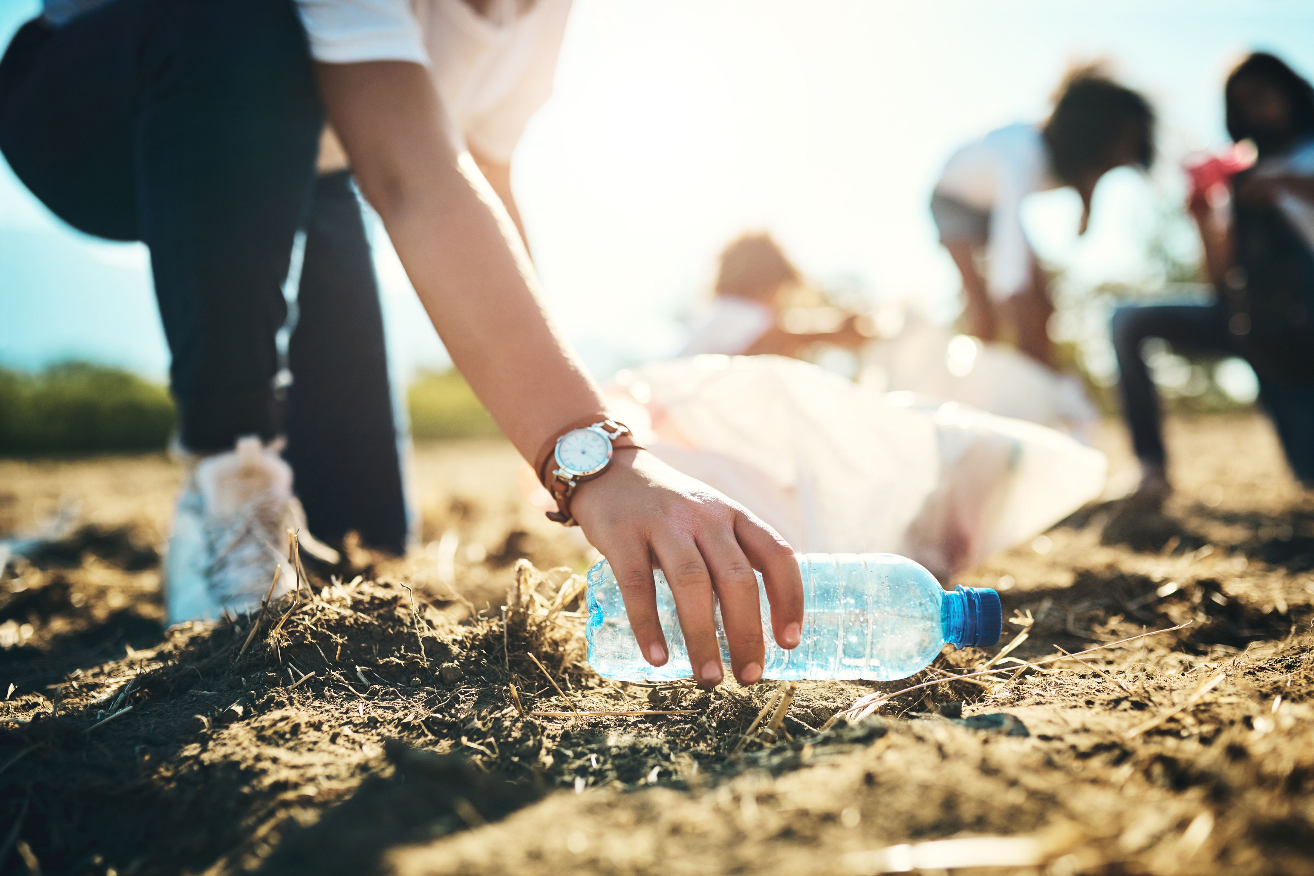 A person picks up trash in their HOA community, trying to reduce their carbon footprint.