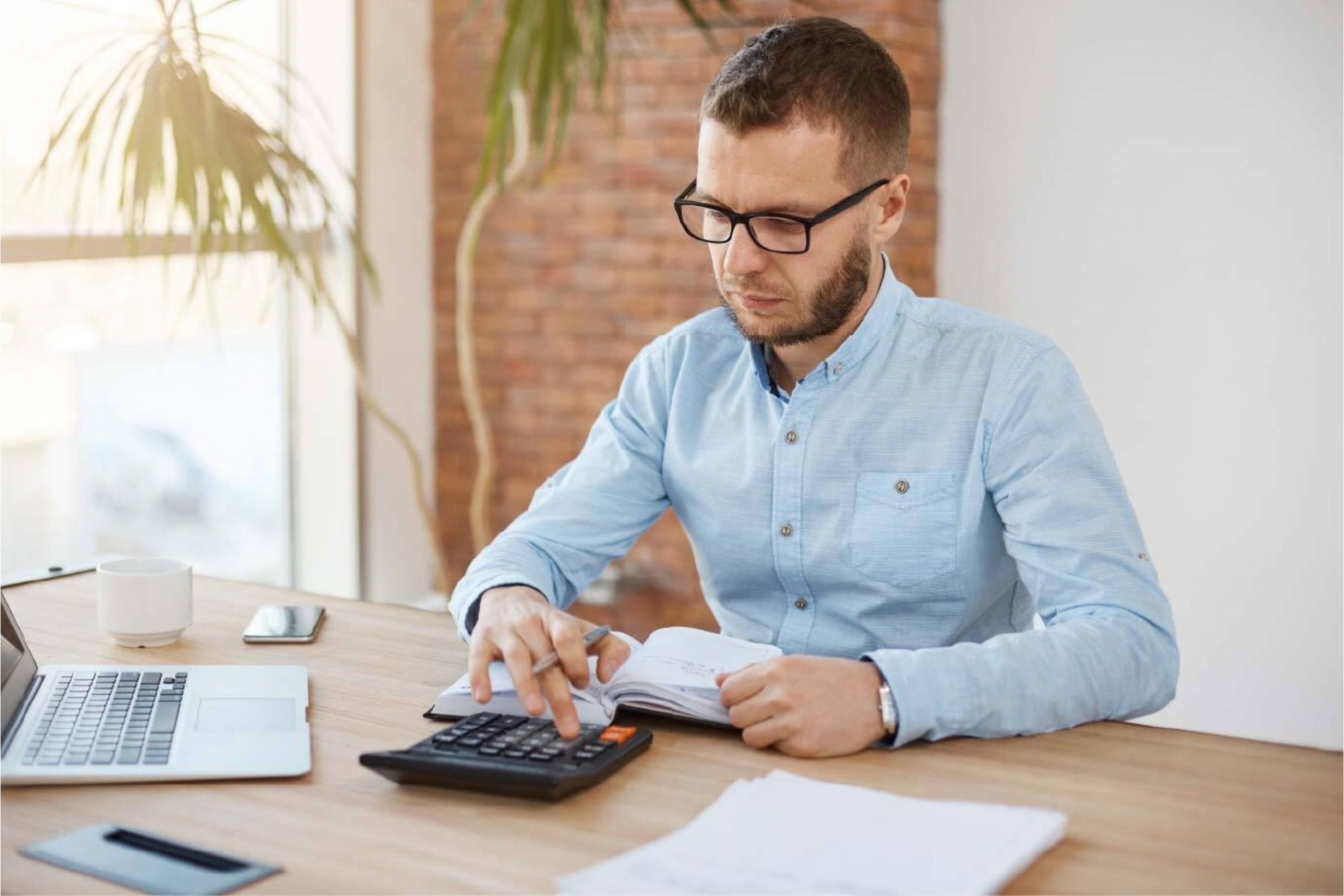 An HOA board member sits at his desk with a calculator working through his community's annual budget.
