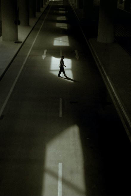 Man crossing a road under a bridge.