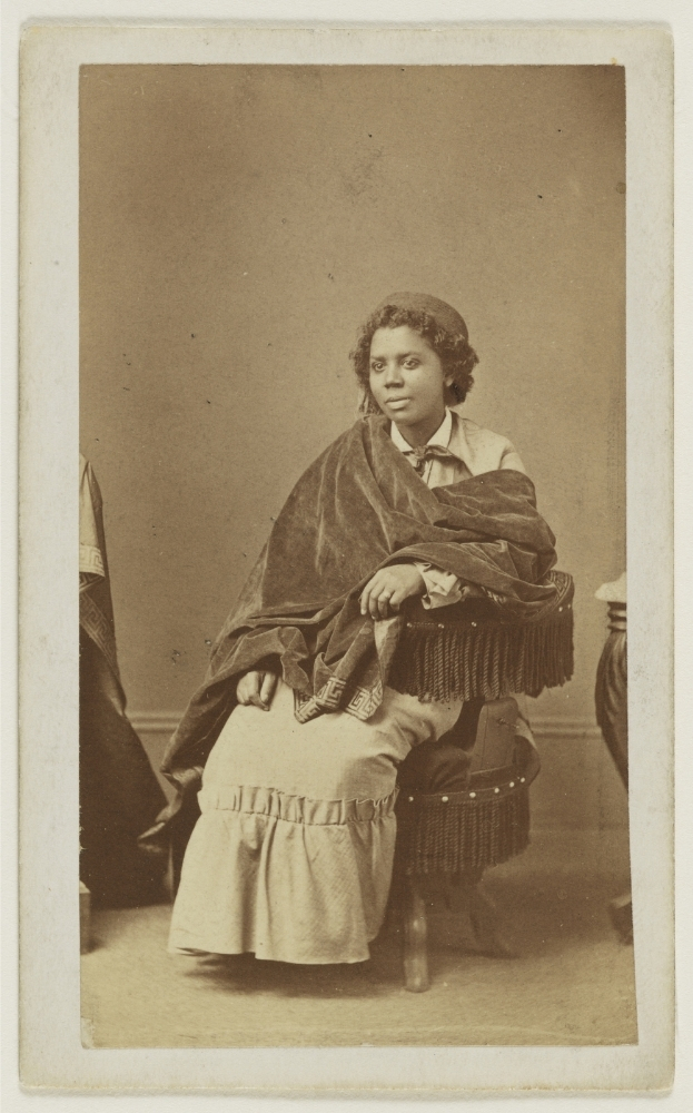 Sepia photograph of Edmonia Lewis around 1870, seated and wrapped in a dark velvet shawl, gazing to the left.
