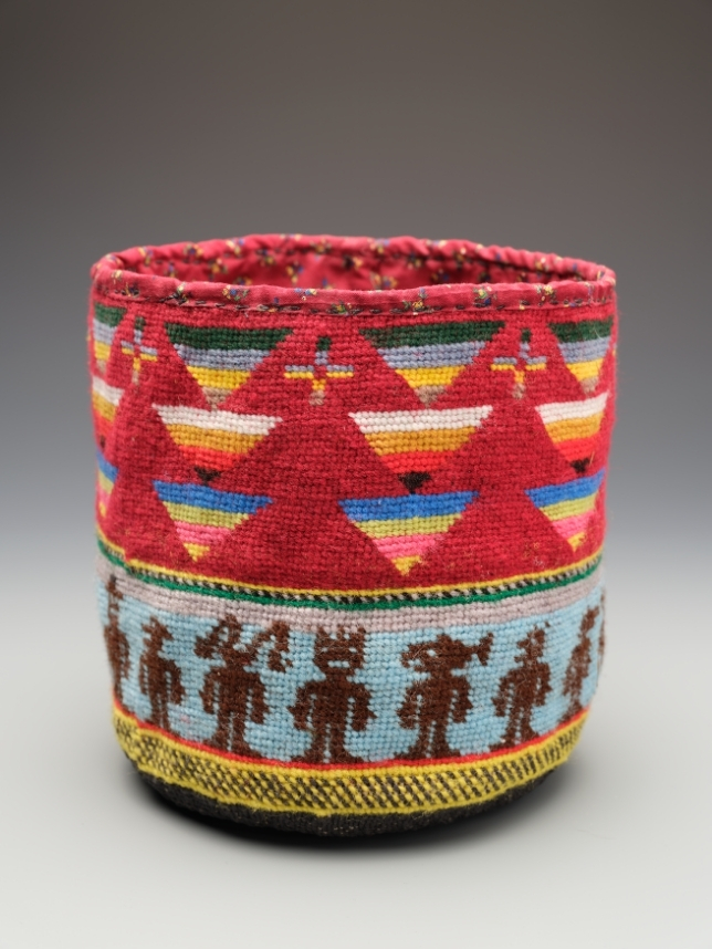 A cylindrical basket with a red top band patterned with yellow, white, and blue triangles, above a pale blue band holding a row of small dark human figures.