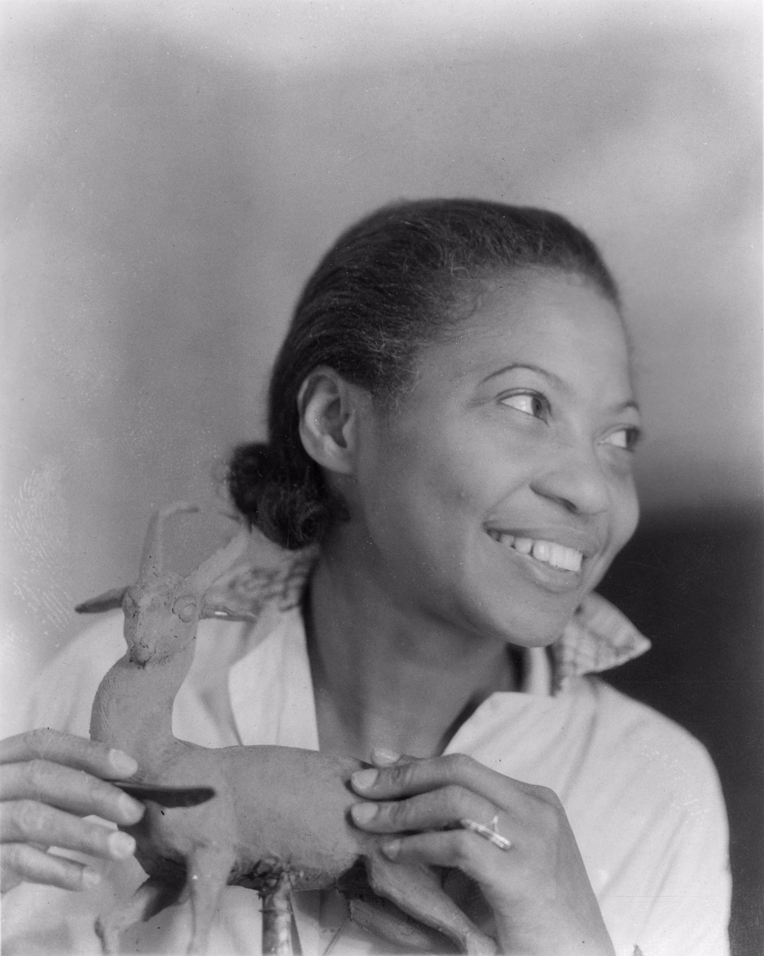 Augusta Savage poses beside her small sculpture of a buck with antlers.