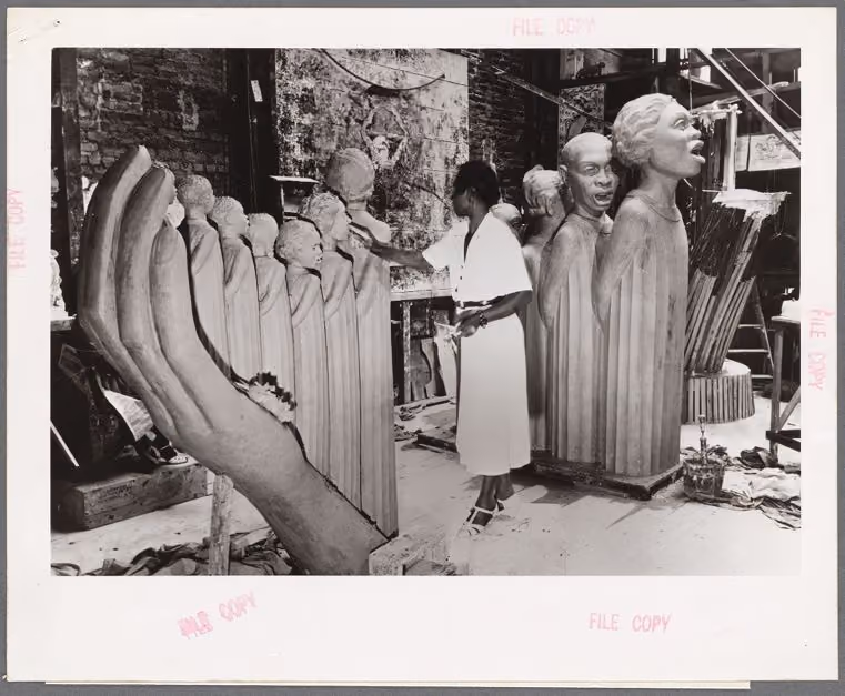 Augusta Savage at work on the large plaster sculpture The Harp, its row of robed singers beside her.
