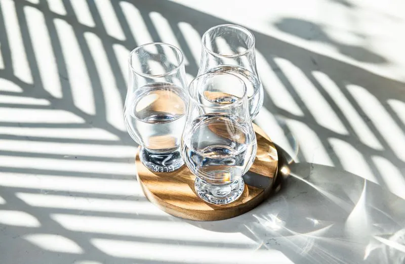 Trio of small glasses with pisco on a clean white table