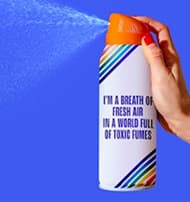 Hand holding a spray can against a blue background