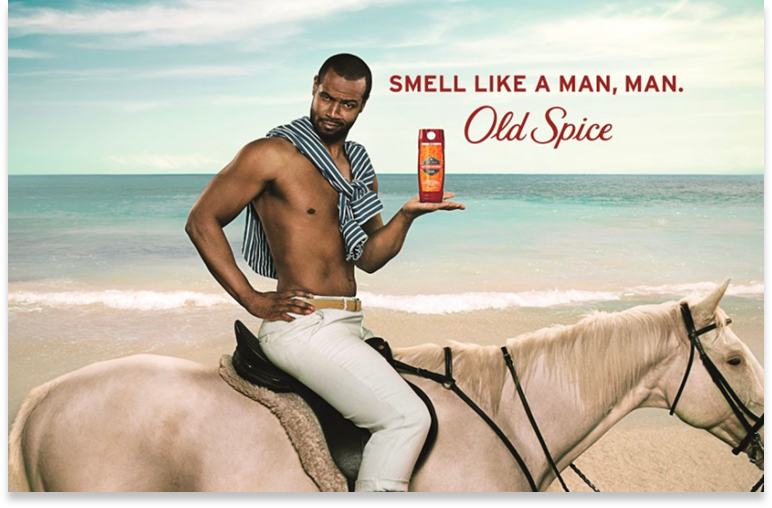 Man riding a white horse on a beach holding an Old Spice deodorant, with the text ‘Smell like a man, man.’