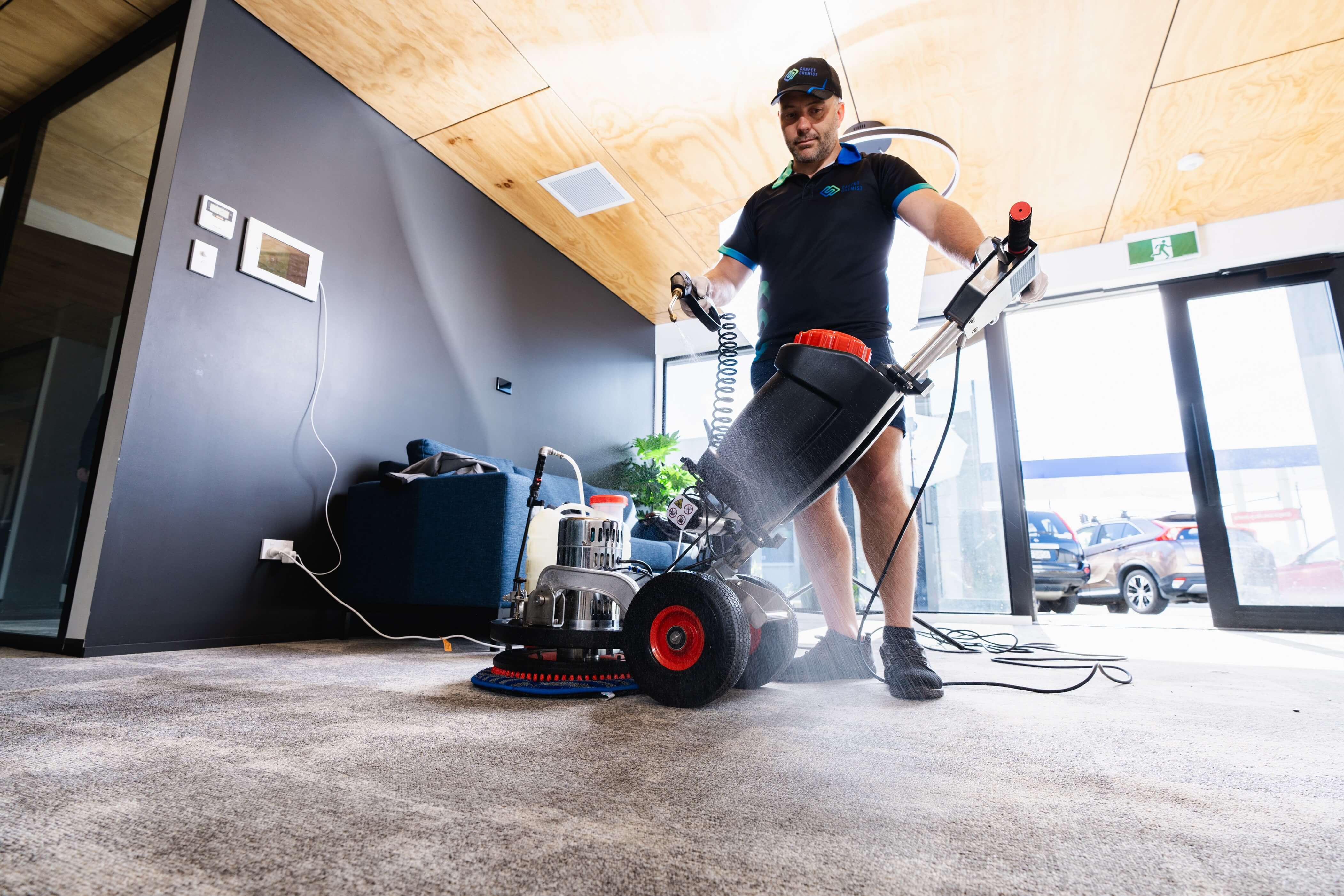 A professional technician uses heavy-duty cleaning equipment to perform deep carpet cleaning and carpet odour removal in a modern office space.