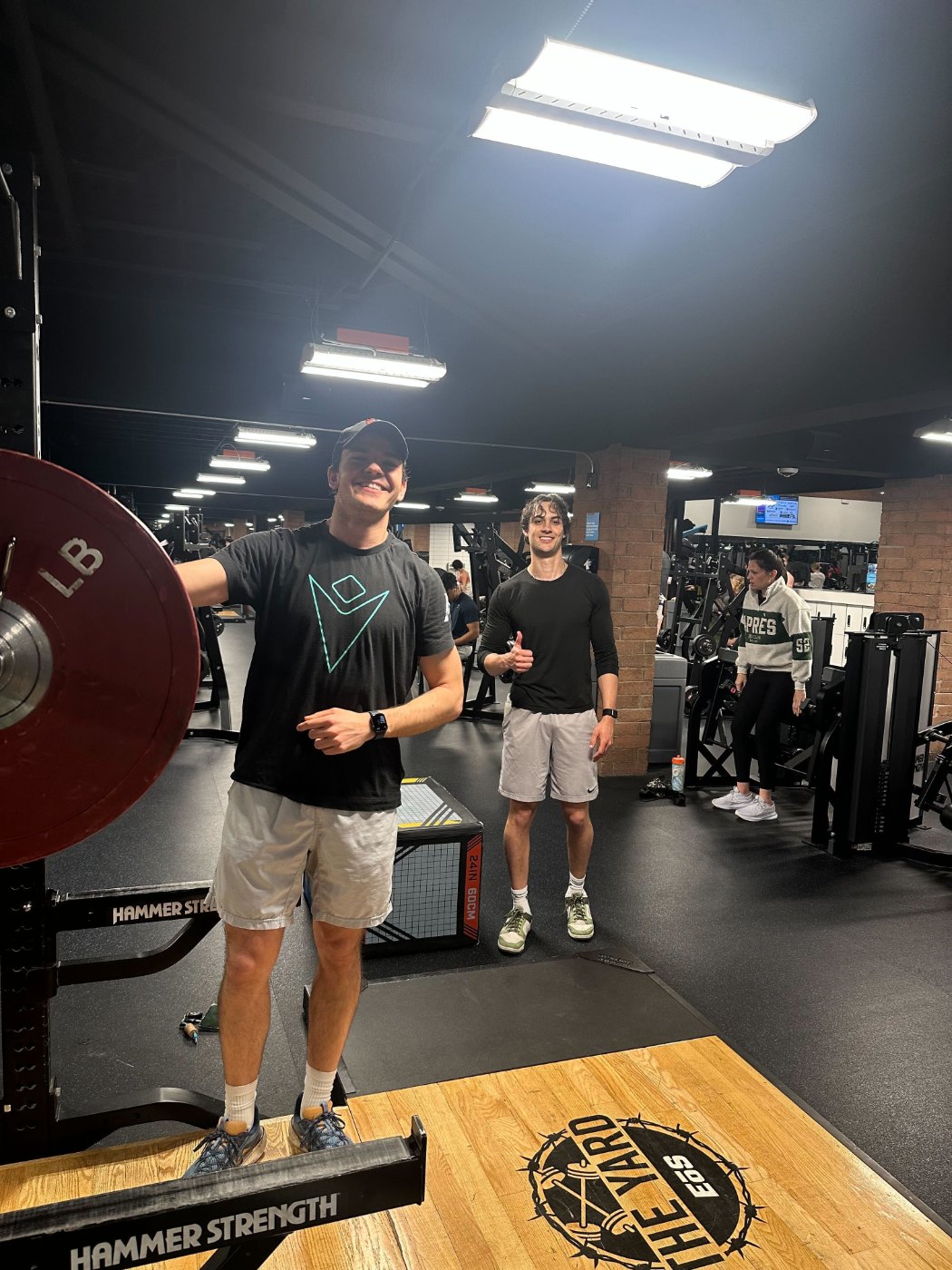 Two Teiko employees at the gym next to a loaded barbell