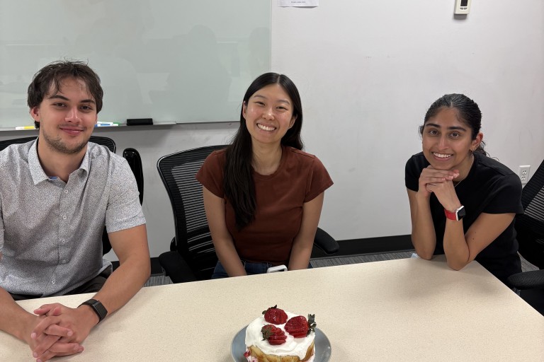Three Teiko teammates at a conference table with a strawberry cake