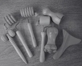 Set of wooden massage tools with different shapes and handles on a wooden surface.