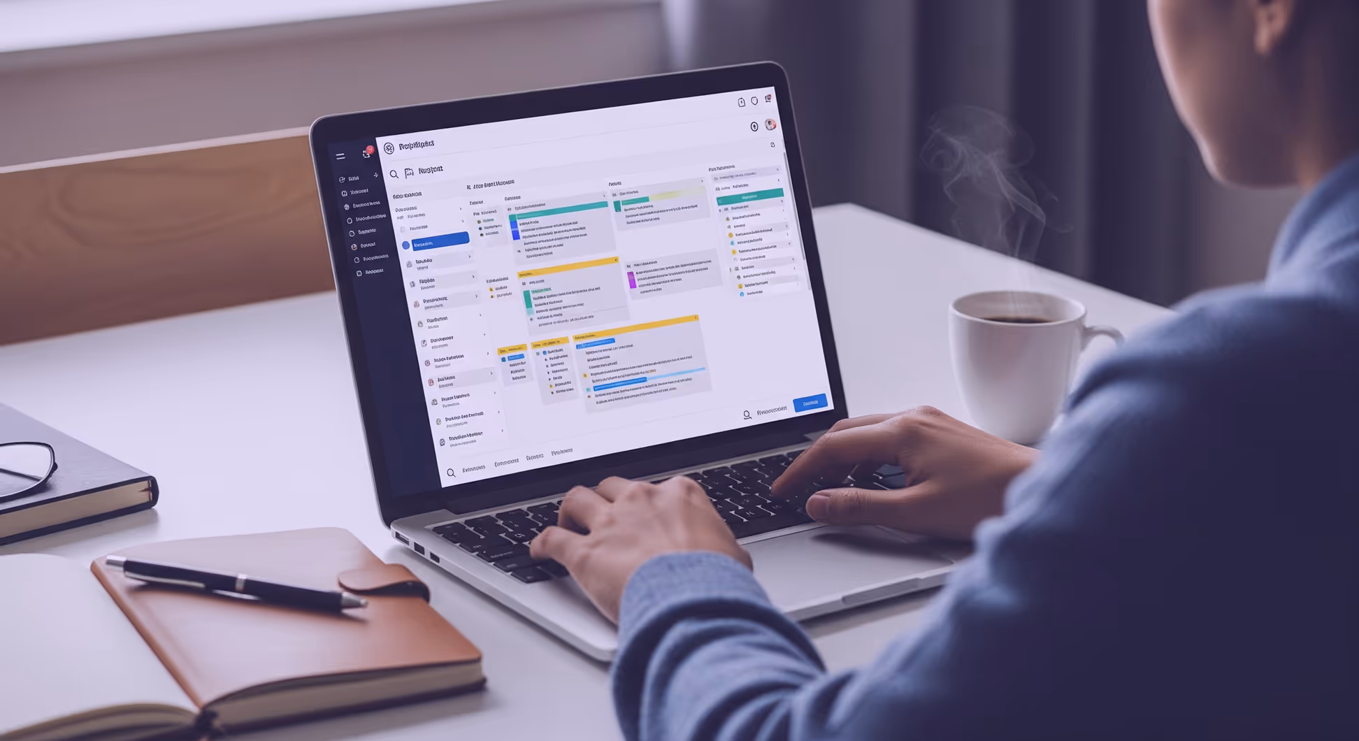 Personne travaillant sur un ordinateur portable avec un outil de gestion de projet, tasse de café et carnet sur un bureau moderne.