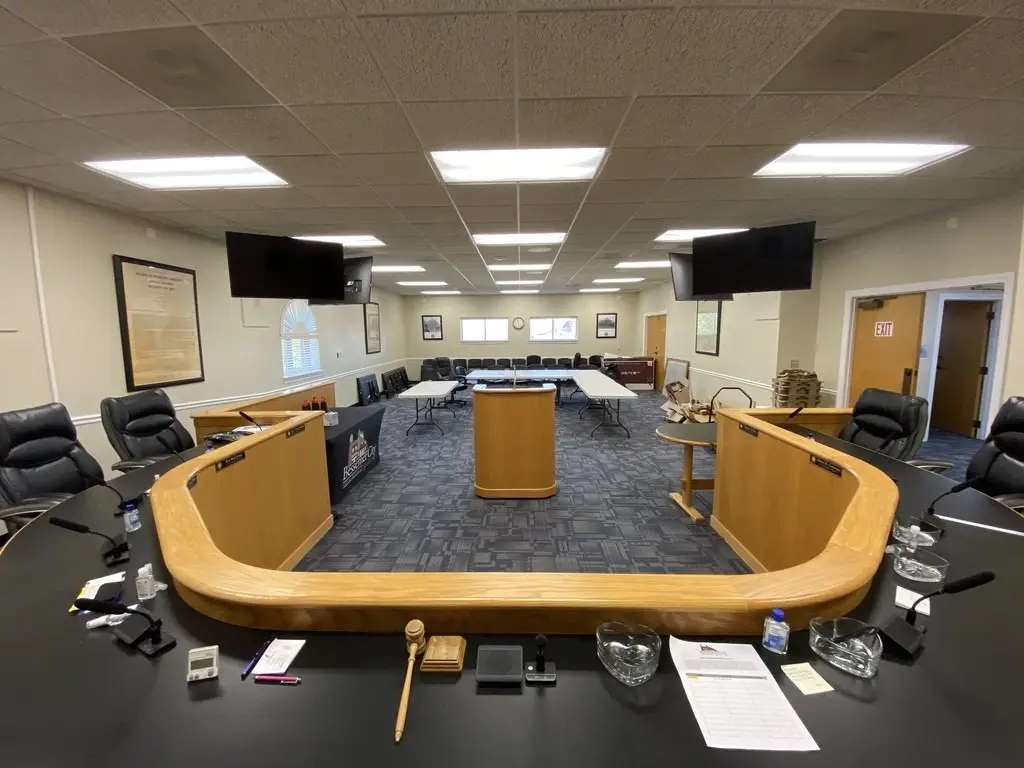 Municipal council chamber with ceiling-mounted AV equipment and curved seating