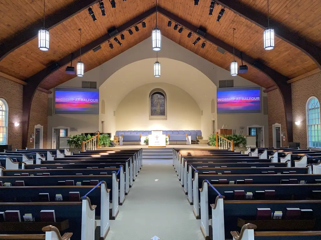 Small church sanctuary with professional AV system including wall-mounted speakers and dual projection displays