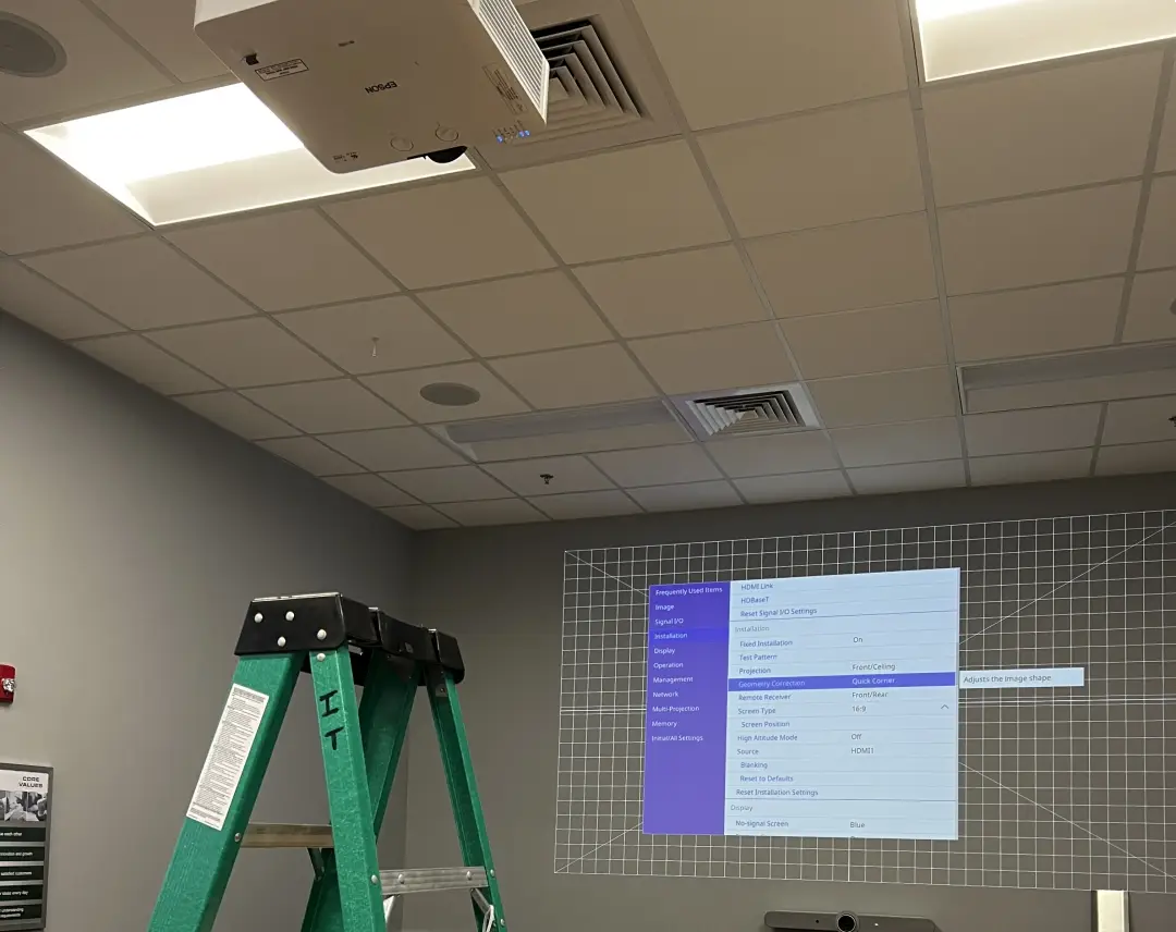 Ceiling-mounted projector installed in a commercial conference room displaying a projected image on the wall