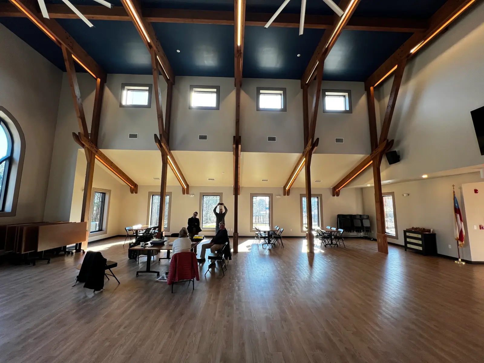 Open church fellowship hall with exposed wood beam ceiling and natural light