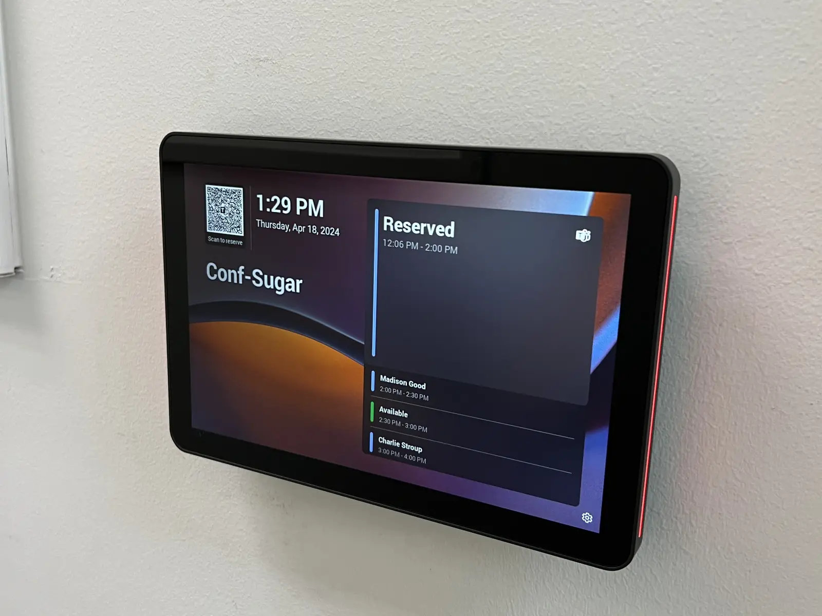 Wall-mounted touchscreen displaying conference room schedule and reservation status