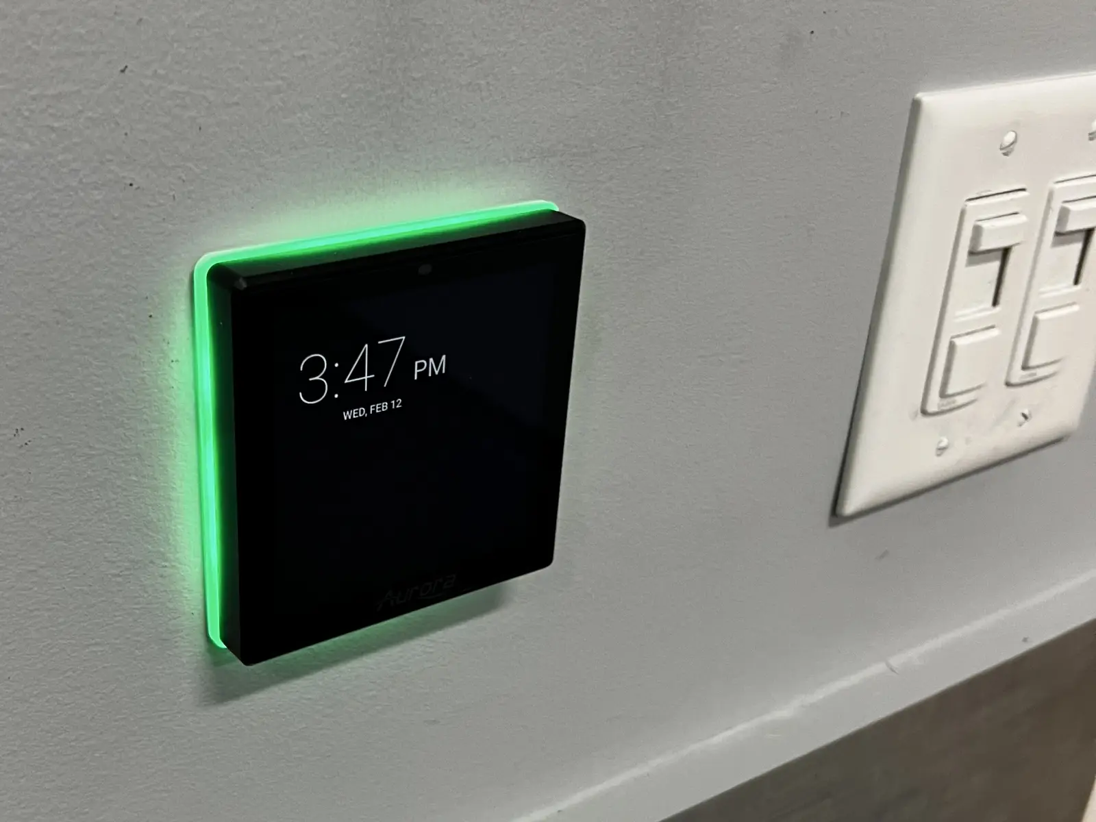 Wall-mounted AV control touchpanel with green LED indicator in a commercial installation