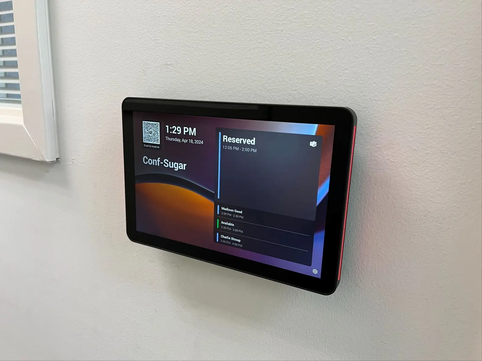 Microsoft Teams Rooms scheduling panel mounted outside a conference room showing the day's reservations
