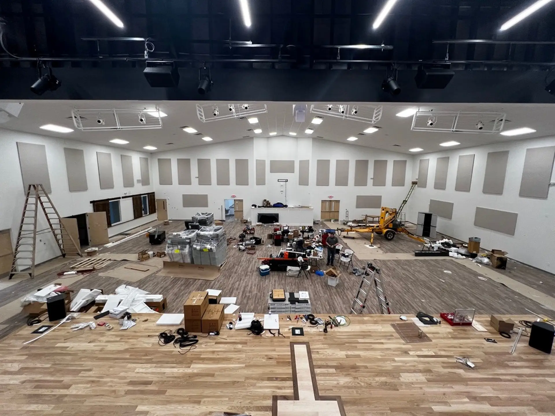 Large church worship space mid-installation with lighting, speakers, and acoustic panels