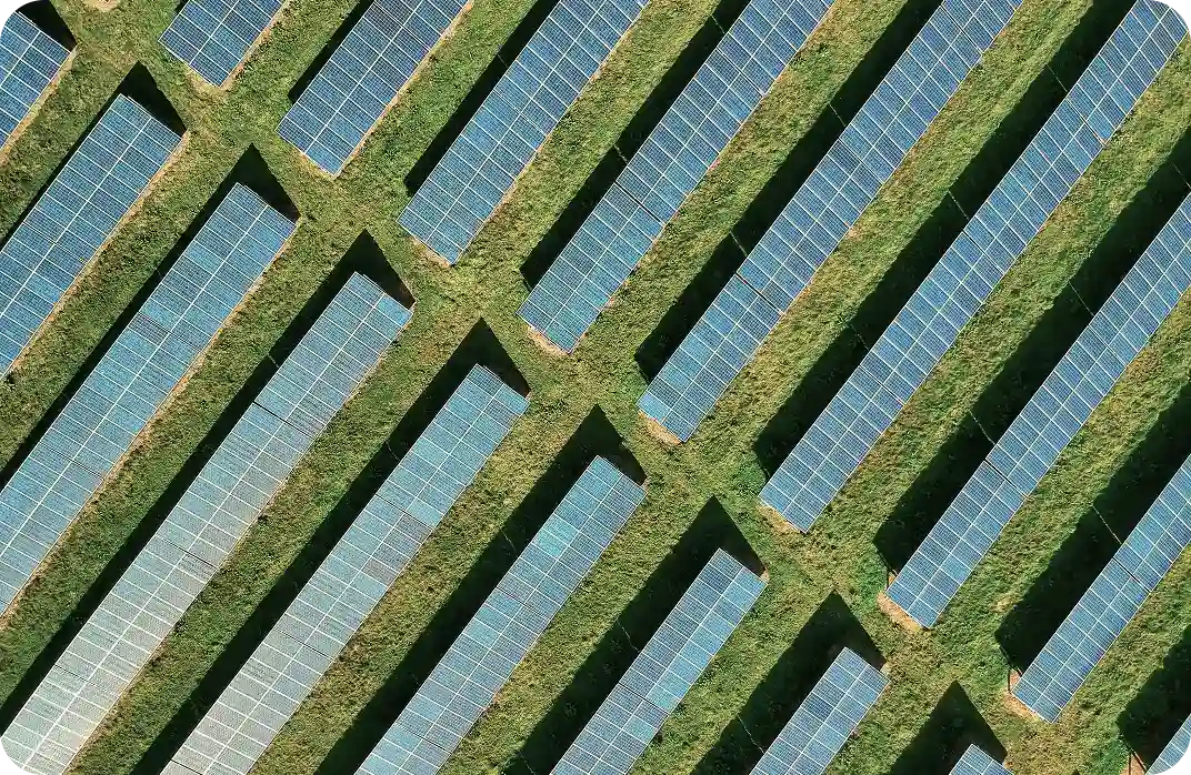 Aurinkopaneeleja pellolla ylhäältä kuvattuna
