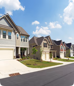 Suburban neighborhood with modern two-story homes, manicured lawns, and a clear blue sky, showcasing residential real estate and community living.