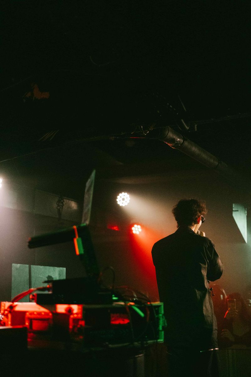 Jimmy Brown seen from behind beside the DJ setup, red and white lights shining over the room