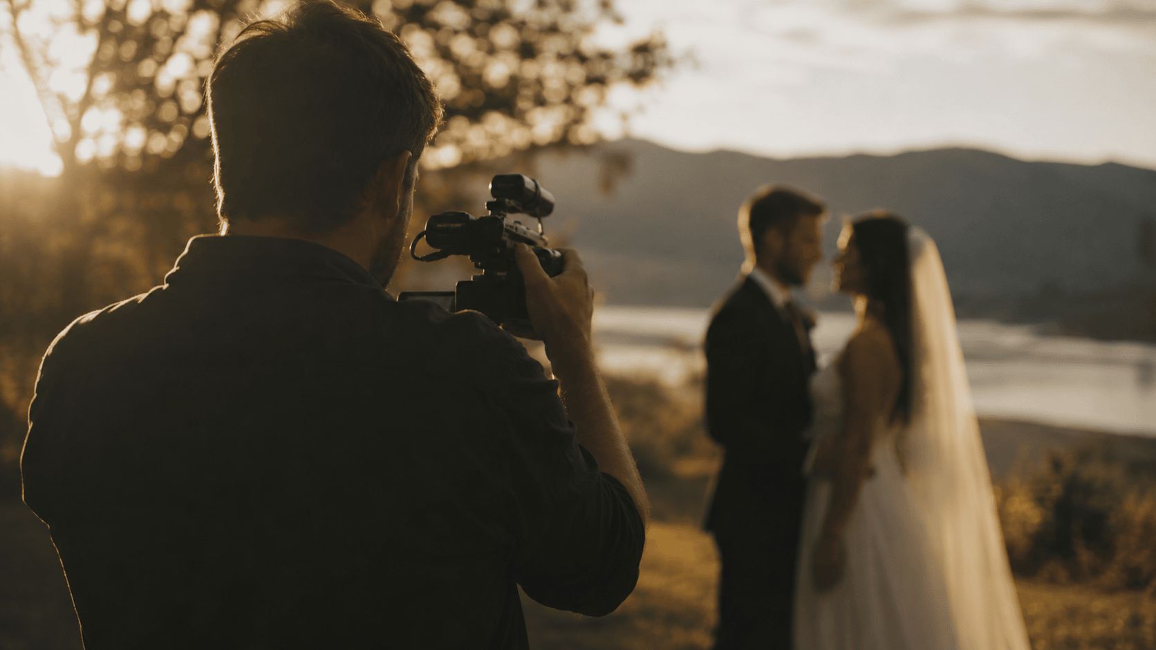 A wedding videographer filming a couple during golden hour, capturing footage for their highlight film